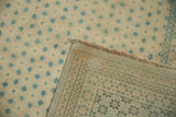Flipped corner of a distressed rug revealing its hand-knotted weave and tidy foundation.