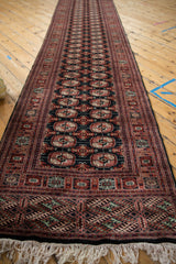 Angled view down the length of a fine Bokhara rug runner with repeating gul medallions.