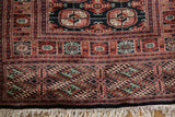 Full ivory fringe below the intricate geometric end border of a vintage Bokhara rug runner.