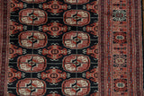 Detailed gul medallions in rust and ivory on the plush black wool of a Bokhara runner.