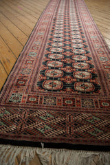 Long perspective view of a vintage Bokhara runner highlighting its repeating gul motif and tidy fringe.