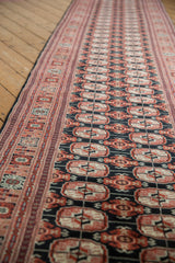 Long perspective of a vintage Bokhara runner showing its columns of geometric gul medallions.