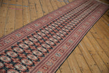 Angled full-length view of the vintage Bokhara runner showcasing its repeating gul motif.