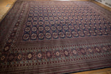 Angled view of a vintage square Bokhara rug showing the lustrous pile and repeating gul pattern.