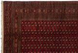 The corner of a vintage fine Bokhara carpet with its intricate geometric border and intact ivory fringe.