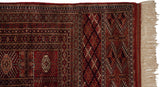 Close-up of the vintage Bokhara carpet's original side cord, geometric border, and ivory fringe.
