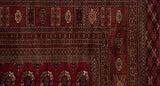 Tight weave and intricate geometric borders at the corner of a vintage cherry red Bokhara carpet.