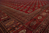 Intricate geometric borders and plush wool pile at the corner of a red Bokhara rug.