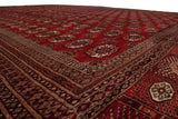 Low angle view of a fine Bokhara carpet's lustrous cherry red pile and repeating gul motifs.