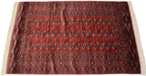 Fine vintage Bokhara rug viewed from an angle, showing its lustrous red pile and gul medallions.