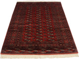 Traditional vintage Bokhara rug viewed lengthwise, showing the lustrous sheen on its dusty red pile.