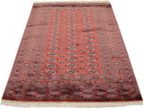 Full length perspective of a fine Bokhara rug with repeating gul medallions on a dusty red field.