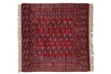 A vintage fine Bokhara square rug with repeating gul medallions in a red, indigo, and ivory palette.