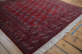 A view across the plush, full pile of a red vintage Bokhara rug with geometric borders.