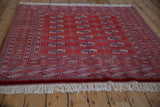 The lush red pile and intricate geometric border of a vintage Bokhara square rug.