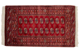 Cherry red Bokhara gul medallions with navy and ivory details, highlighting the fine weave.