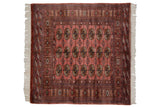 The tight geometric grid of gul medallions on a dusty rose Pakistani Bokhara rug.
