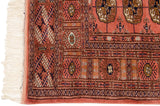 A detailed corner view of a fine Bokhara rug, showing the intact side cord and plush, dusty rose pile.