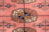 Finely knotted gul medallion in navy blue and ivory against the plush, dusty rose wool pile.
