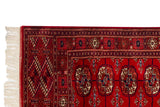 Ivory fringe and geometric gul medallions on the plush cherry red pile of a vintage Bokhara runner.