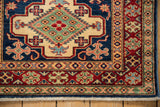 Hand-knotted Pakistani Caucasian rug corner, showing vibrant indigo, red, ivory geometric borders and fringe.