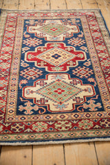 Clear geometric floral motifs in indigo, cherry red, and ivory on the wool pile.