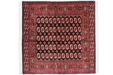 Vintage Bokhara carpet with red and ivory gul medallions on a black field, framed by detailed geometric borders.