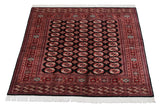Angled view of a fine Bokhara carpet, showcasing the sheen on its dense, geometric gul pattern.