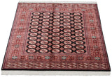 The full design and lustrous pile of a vintage Bokhara carpet viewed from an angle.