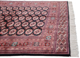 The intricate rust and black geometric borders and original ivory fringe on a fine vintage Bokhara carpet.