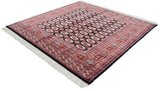 Angled view of a fine Bokhara carpet, showing the lustrous pile and repeating rust and ivory gul medallions.