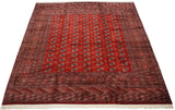Angled view of a vintage Bokhara carpet showing the lustrous red field and intricate geometric borders.