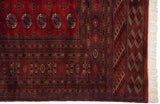 Vintage Bokhara carpet corner showing the fine weave, intricate geometric borders, and original ivory fringe.