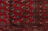 Corner view of a vintage Bokhara carpet showing its multi-layered border and geometric gul medallions.