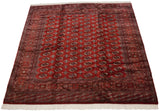 Angled view of a vintage Bokhara carpet's lustrous red pile and rows of geometric gul medallions.