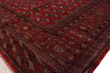 Angled view showcasing the tight weave and intricate border of a vintage red Bokhara carpet.