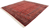 Angled view of a fine Bokhara square carpet highlighting its lustrous cherry red wool and geometric pattern.