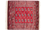 The symmetrical grid of gul medallions on a vintage red Bokhara rug with intricate geometric borders.