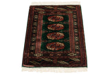 Angled view of a vintage Bokhara rug highlighting its plush green pile and rust medallions.