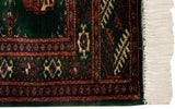 Fine Bokhara rug corner with plush green pile, rust geometric motifs, and thick ivory fringe.