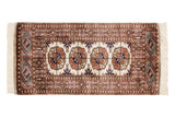 A flat view of the vintage Bokhara rug's detailed gul medallions and intricate geometric borders.