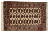A vintage fine Bokhara rug with repeating gul medallions in copper and navy on a lustrous ivory field.