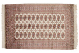 The tight, fine weave of a vintage Bokhara rug, showing rows of geometric gul medallions.