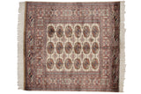 Detailed geometric floral gul medallions in camel, navy, and ivory Bokhara rug.