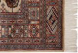 Vintage Bokhara rug border featuring geometric camel, navy, and copper patterns with ivory fringe.