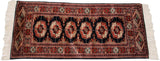 Repeating rust and ivory gul medallions on a black Bokhara runner with fine weave.