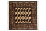 Vintage Bokhara square rug with repeating gul medallions in navy and gold on a plush ivory field.