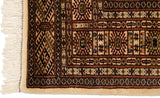 Corner of a fine Bokhara rug highlighting the plush pile, intact side cord, and ivory fringe.