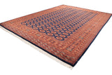 Navy blue and copper gul medallions, geometric borders, and ivory fringe on a Bokhara rug.