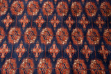 Intricate Bokhara gul medallions in copper rust, ivory, and navy blue.